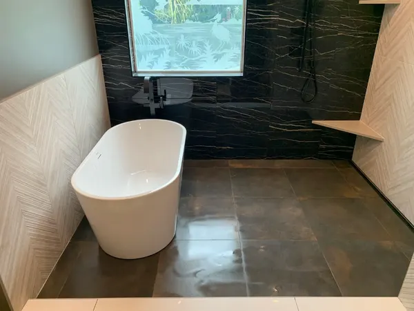 Custom Walk-in Shower — Light chevron accent wall paired with deep black marble veining and modern matte black hardware.