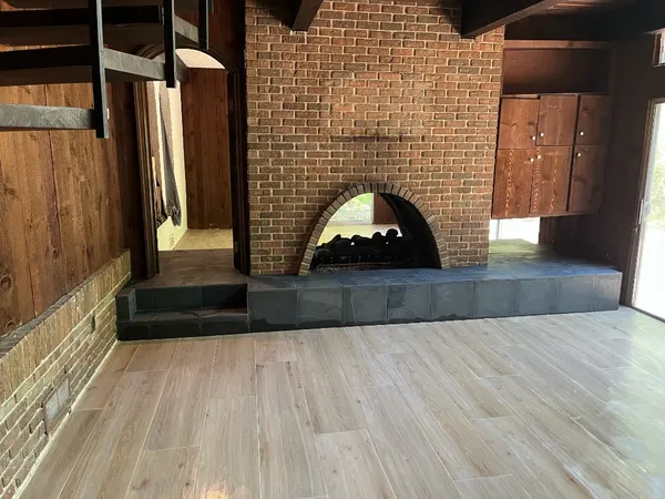 Wood-Look Plank Living Room Floor — Wood-look porcelain plank installed in a staggered layout, meeting a slate hearth with clean transitions.
