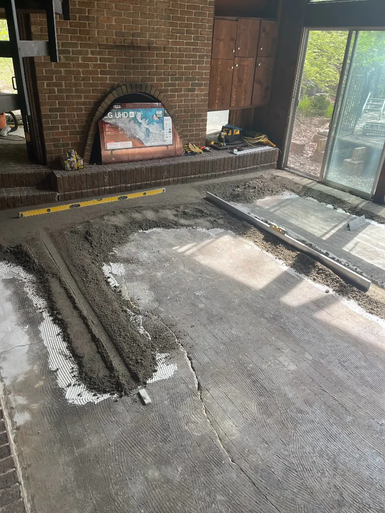 Mortar bed screeded and thinset combed out across the slab with levels and screed rails in place